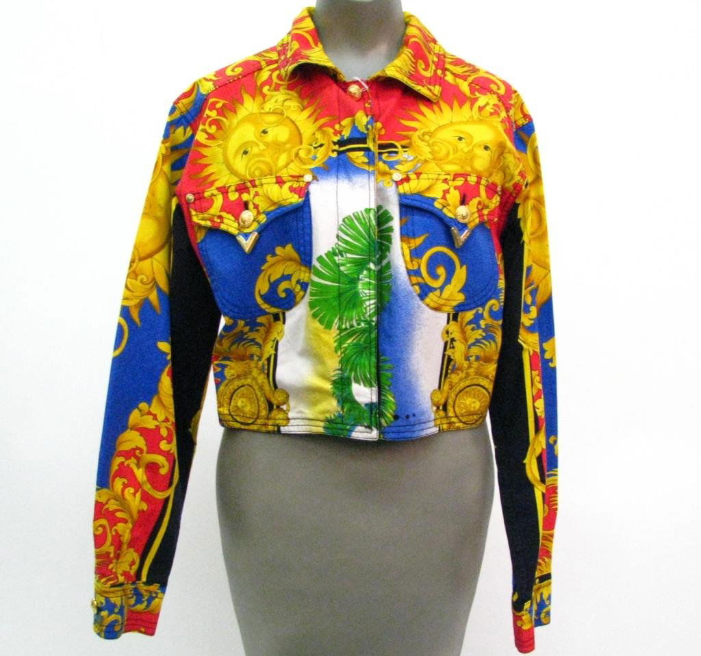 Versace Jeans Couture, Multi-Color: Versace Jeans Couture rare vintage multi-color baroque and sun design jean jacket. Four hidden black buttons down front with top sunburst button. Two front flap pockets with buttons; Size Medium