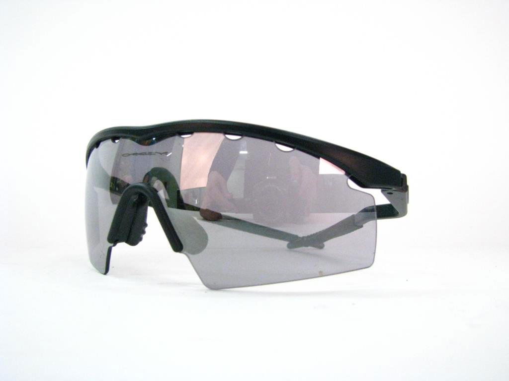 Oakley Classic Unisex Sunglasses: Oakley classic unisex shield sunglasses with gray mirror lens and black folding arms. Lens reads "Oakley" right above cushioned nose piece