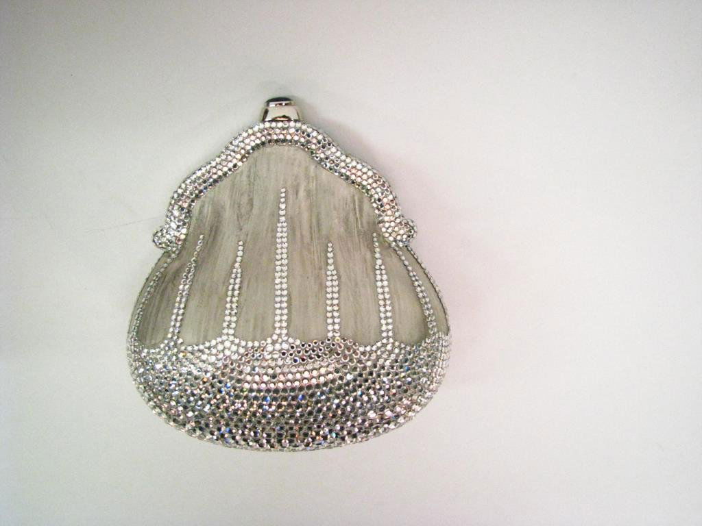 Judith Leiber Brushed Silver Pear Shape Minaudiere: Judith Leiber brushed silver "pear" shape minaudiere with black onyx clasp. Purse features brushed metal set with clear crystals. Interior is silver and has attached thin twist shoulder strap. Include