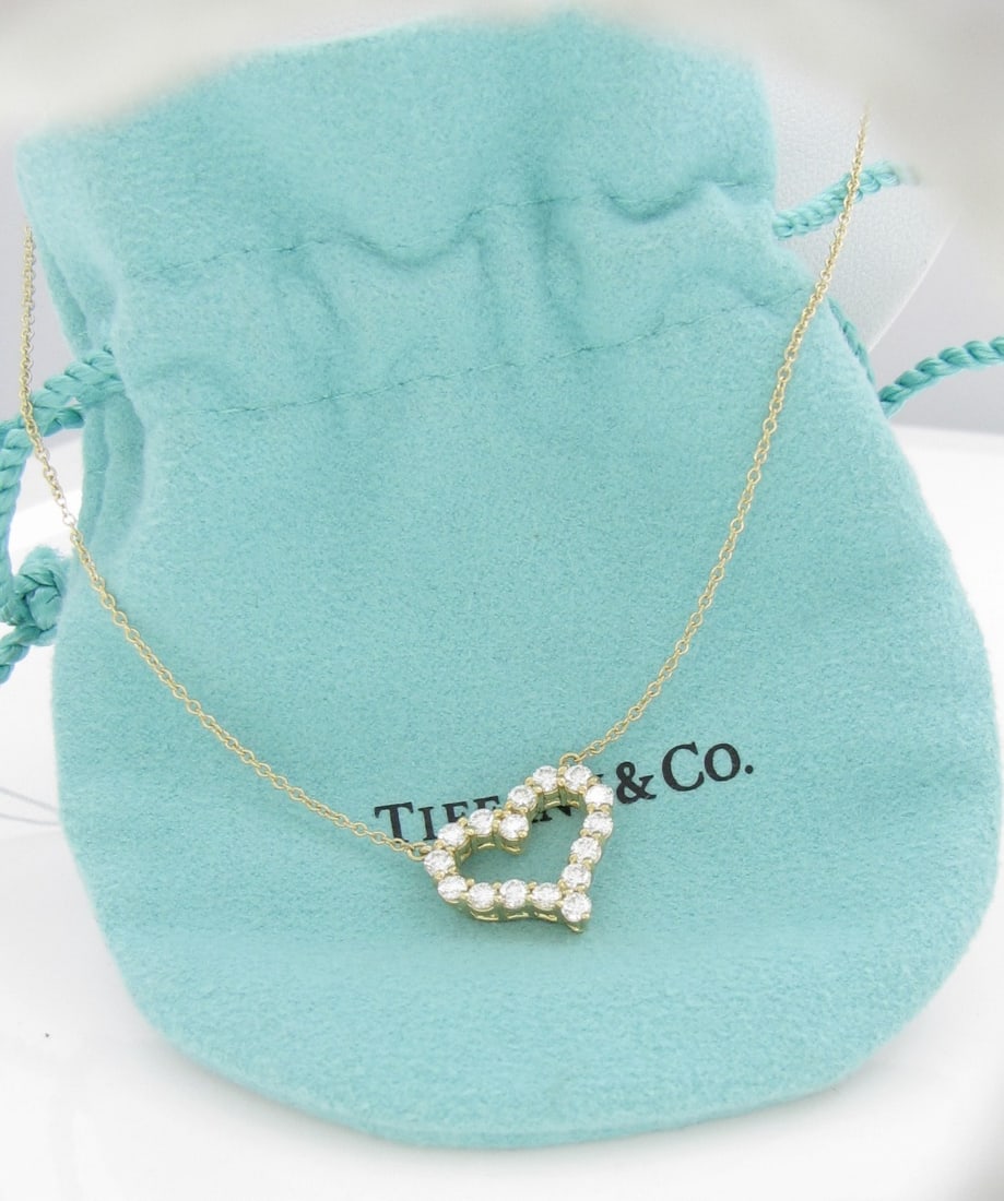 18K YG Tiffany & Co Diamond Heart Necklace: An 18K yellow gold Tiffany & Co. heart necklace containing eighteen round, brilliant cut, .03ct diamonds. Total diamond weight approximately .54ctw. Necklace is 20" long. Pendant measures