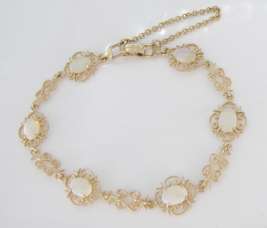 14K YG Filigree Style Opal Bracelet: A 14K yellow gold, filigree style bracelet containing six 7mm x 5mm oval white opals. Bracelet weight 4.3dwt. Approximately 6.75" long.