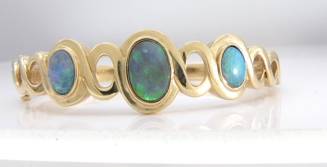 14K Yellow Gold Boulder Opal Bangle Bracelet: A 14K yellow gold bangle bracelet with bezel set oval boulder opal. Approximately 6.25" interior circumference, approximately 15.5mm wide at front center. Bracelet weight 22.4dwt. Retail $7,950