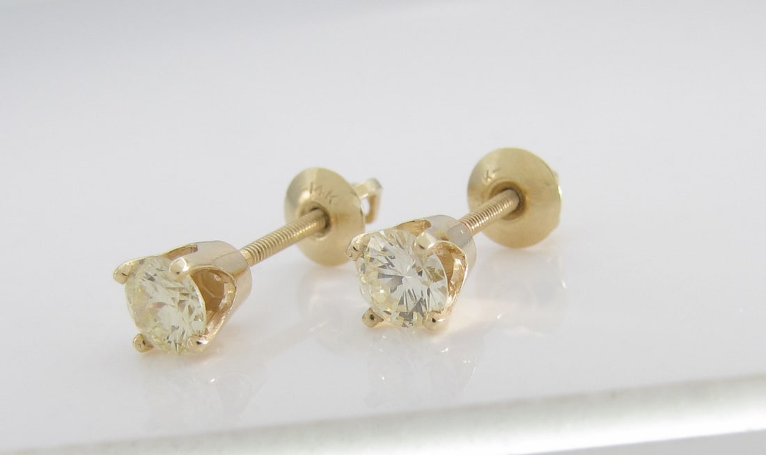 14K Yellow Gold Diamond Stud Earrings: A pair of 14K yellow gold stud earrings featuring two approximately .43ct round brilliant cut diamonds of SI clarity and J-K color, with screw back posts. Total diamond weight approximately .85ctw.