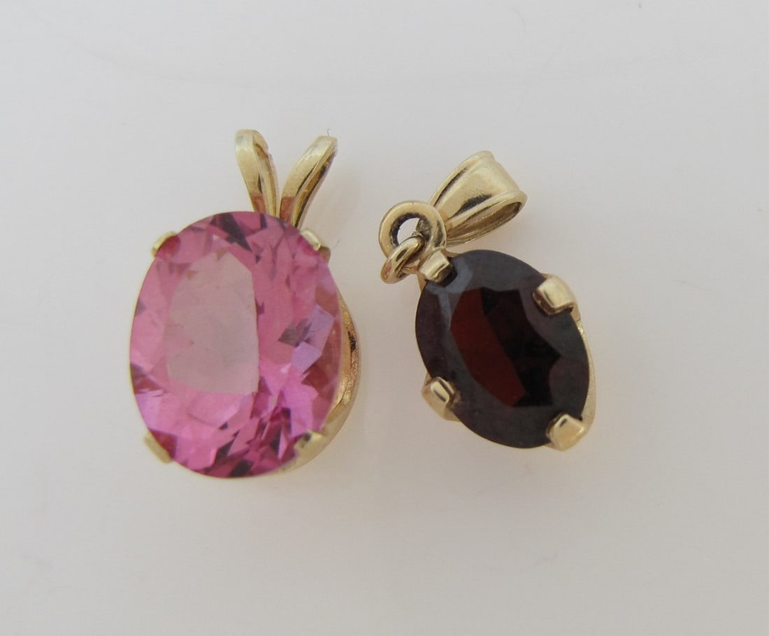 Two 14K Yellow Gold Pendants: Two 14K yellow gold pendants including a .50" x .25" pendant with oval 10mmx8mmx4.75mm pink stone, .7dwt; and a .63" x .25" pendant with an 8mm x 6mm x 3mm garnet, .4dwt.