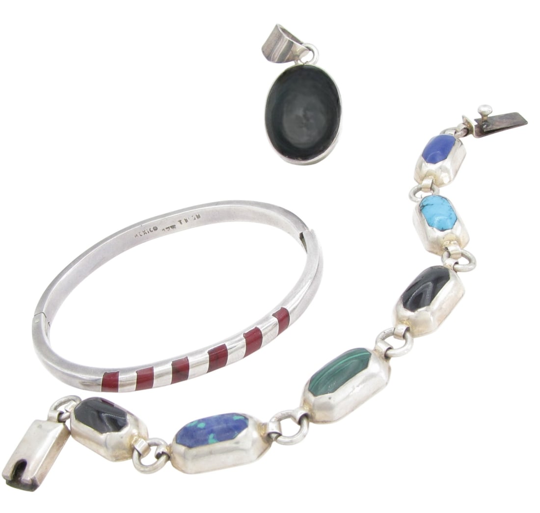 Three Sterling Taxco Mexico Jewelry Items: Three sterling silver Taxco Mexico jewelry items including a 1.75" x .75" pendant with cabochon black onyx, marked "TA-113"; a single hinged bangle bracelet with red jasper? inlay, approximately 7"