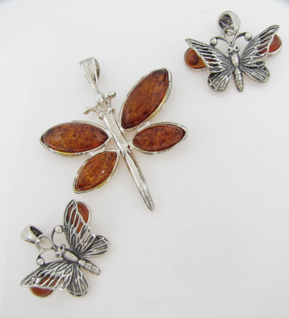 Sterling Amber Butterfly and Dragonfly Pendants: A group of sterling silver pendants including two .88" x 1" butterfly pendants, each with two approximately 8mm x 5.5mm pear shaped cabochon amber stones, 2.1dwt and 2.2dwt; and a 1.75" x 1.5"