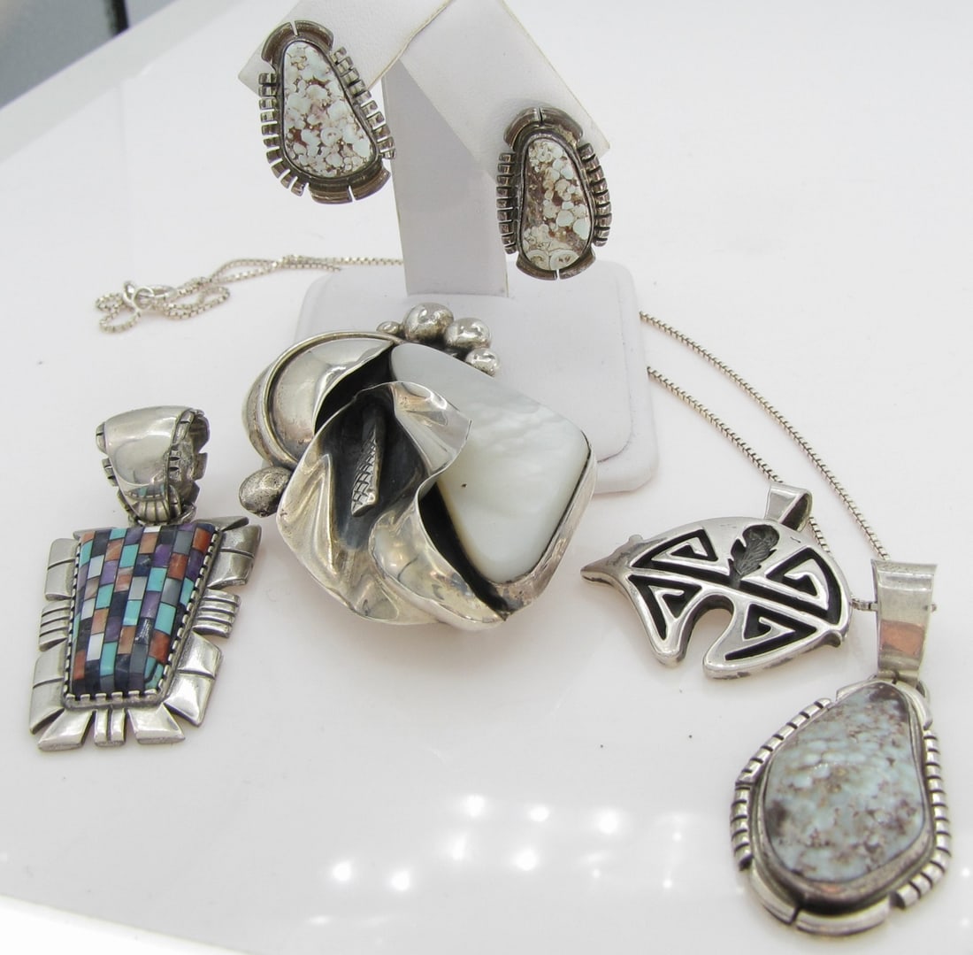 Native American Artisan Sterling Jewelry: A group of Native American sterling jewelry by highly collectible artisans including: Larry Sandoval mother-of-pearl brooch, 2.25" x 1.5"; Carolyn Pollack Relios 2" x 1" mosaic inlay pendant with