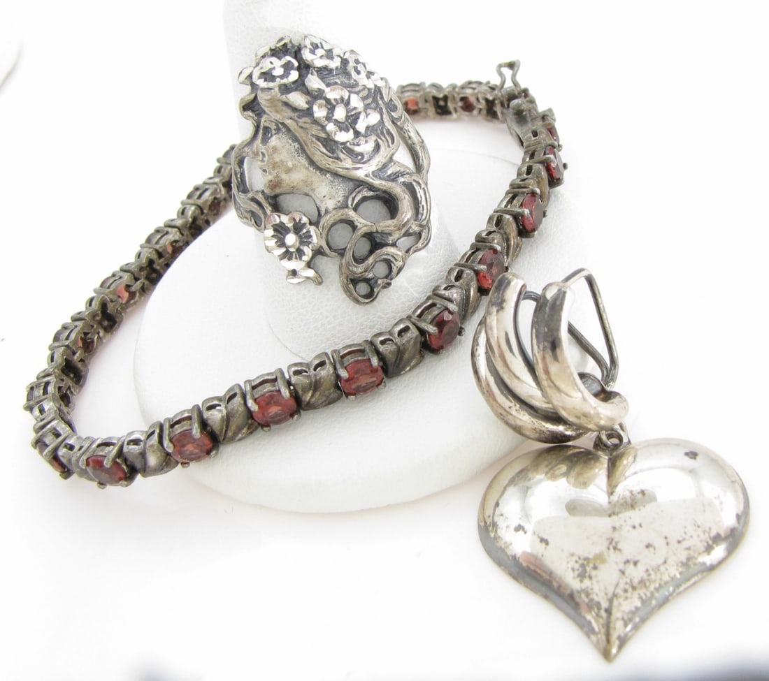 Three Sterling Silver Jewelry Items: Three vintage sterling silver jewelry items including an approximately 7" long link bracelet with approximately twenty-one orange-red garnet colored stones, bracelet width 4.3mm; a 1.5" x .9" heart