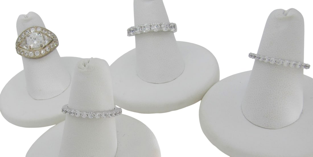 Four Sterling Silver Cubic Zirconia Rings: Four sterling silver rings with Cubic Zirconia including a CNA sterling ring with Domique cubic zirconia including round center stone, two trillion side stones and twenty-six round pave set, in a