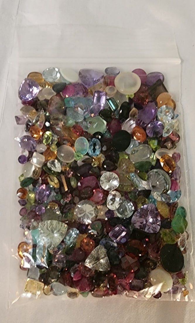 Bag of Loose Gemstones: A bag of loose gemstones including stones with the appearance of amethyst, garnet, mother of pearl, onyx, peridot, orange sapphire, citrine and more. Stones are professionally unidentified. In