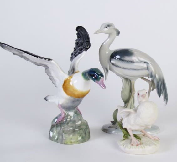 Three Porcelain Bird Figurines: A group of three porcelain bird figurines, including a German Kunstporzellane crane figure, 7.5" tall, a Staffordshire porcelain duck (tip of wing repaired), 7" tall, and a Cybis bisque baby duck figu