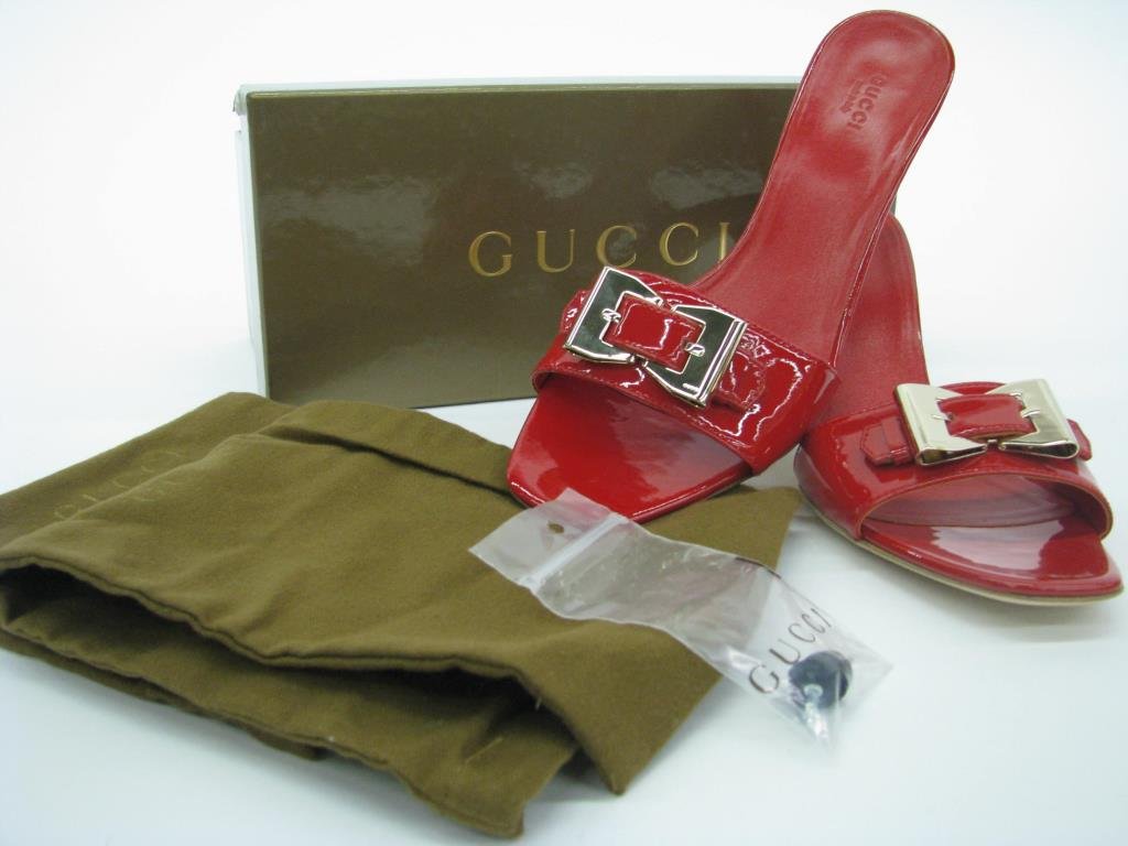 Pair Gucci Red Patent Leather Slides: Pair of Gucci red patent leather slides with silver tone bow buckle detail. 3" heel. Includes Gucci box, dust bags and extra heel tips. Size 10B