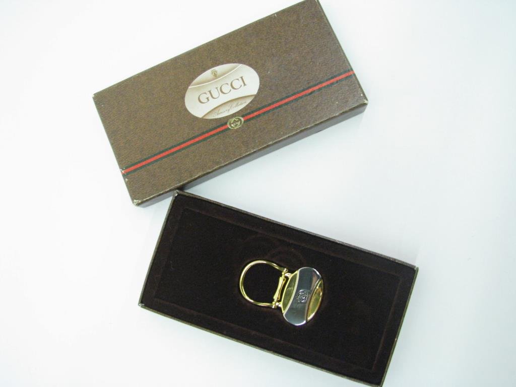 Gucci Gold and Silver Door Knocker Key Chain: Vintage Gucci gold tone with silver tone center bar "door knocker" style key chain with logo. New in original box. 2" tall and 1 3/8" wide