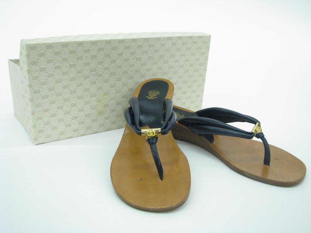 Gucci Navy Sandals: Pair of vintage Gucci navy thong style sandals with slight wood wedge heel and gold tone hardware. Never worn. Size 37 in vintage box