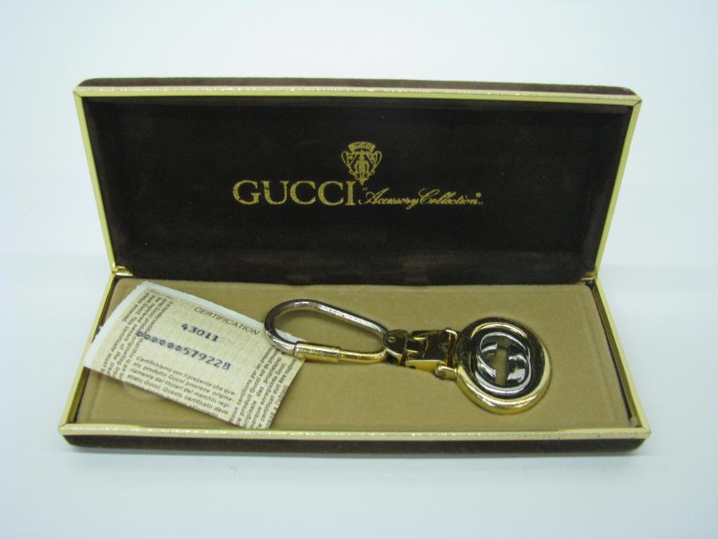 Vintage Gucci Key Chain: Vintage Gucci two tone keychain. At the bottom of the hinged key chain is one open oval with swivel logo. It is 1 1/2" x 1 1/4" and 3 1/2" long. (shows wear). In original Gucci Accessory Collection br