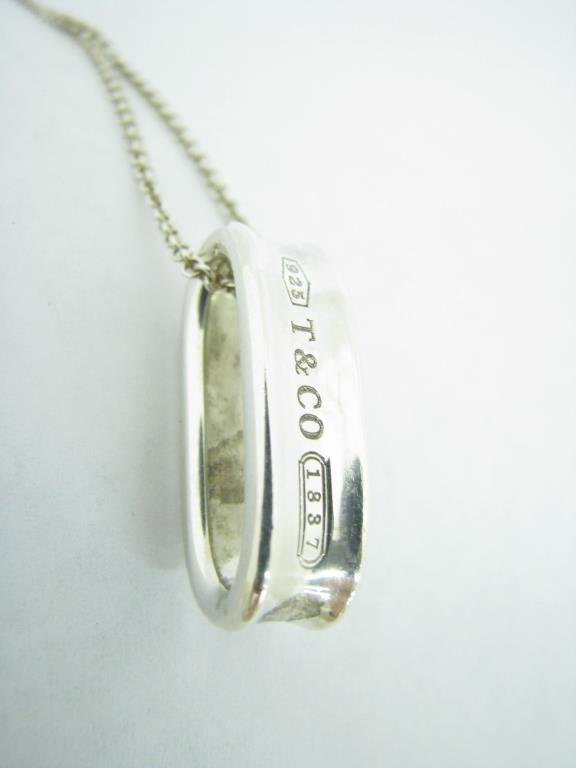 Tiffany Sterling "T & Co. 1837" Pendant: Tiffany & Co. "T & Co. 1837" sterling loop pendant on 18" sterling silver chain with lobster claw clasp. Pendant is 1" long. Both pieces marked T & Co. 925