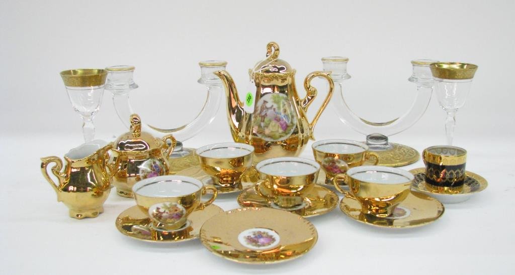 Group of Gold Decorated Tableware: A group of gold decorated tableware including a porcelain tea service with scenic decoration (missing one cup); two gold trimmed wine stems; pair of two-branch candlesticks; and German demitasse cup a