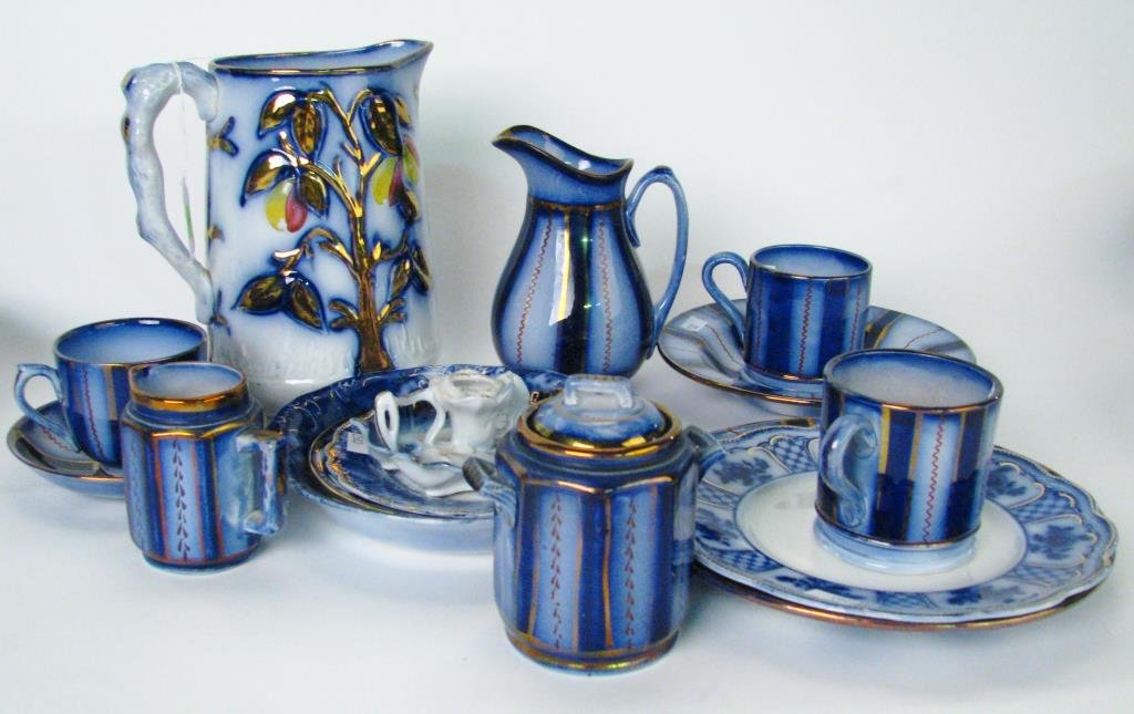 Group of Antique Flow Blue Porcelain: A group of antique Flow Blue porcelain including cream pitcher (repaired handle), milk pitcher, coffee cups, sugar bowl, candle holder and seven plates and bowls of various sizes