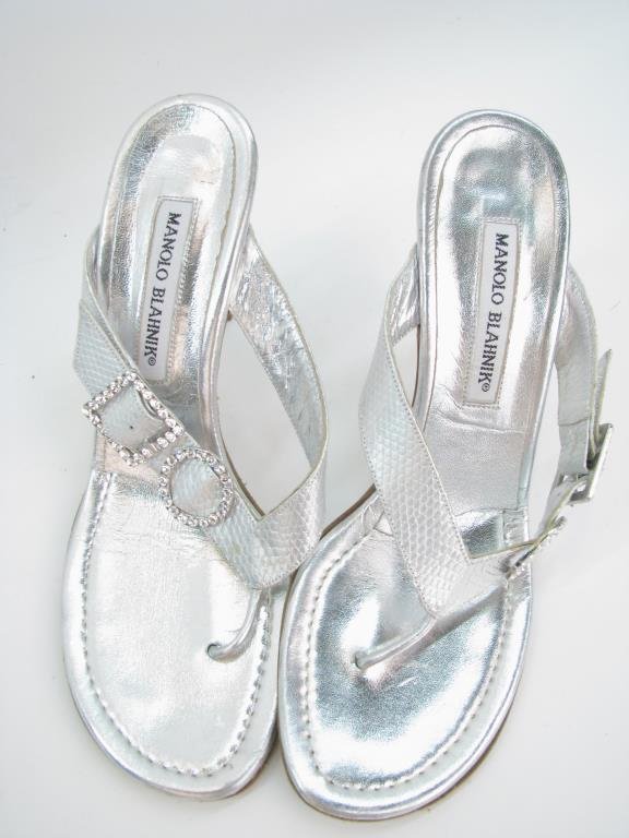 Manolo Blahnik Silver Slides: Manolo Blahnik silver slides with rhinestone accents. Textured metallic silver leather with ring adorned with rhinestones and square rhinestone adorned buckle. 2" heel. Size 39.5