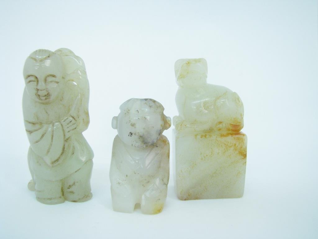 Three Small Chinese Jade Carvings: A group of three, small, Chinese jade carvings including one Foo Dog on base, 2.25" high; one male figure with dog; and one child figure