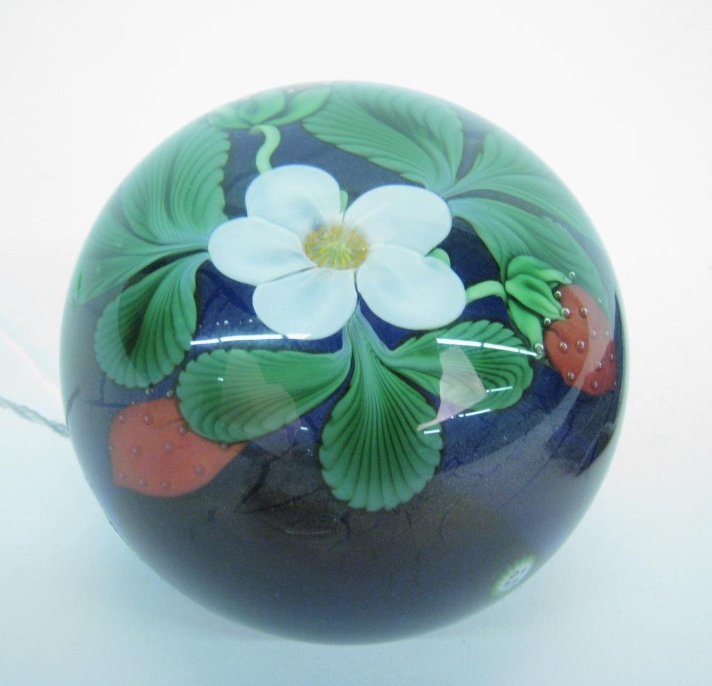Orient & Flume Strawberry Plant Paperweight: An Orient & Flume strawberry plant paperweight with white bloom and three fruit on clear top over graduated iridescent colors bas, signature cane "of 84" above foot, signed & inscribed CV 35/500 1984