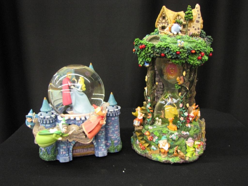 Two Disney Snow Globes: Two Disney Snow Globes depicting Scenes from Snow White (hour glass snow globe) and Scenes from Cinderella, 8-12" tall, with original boxes