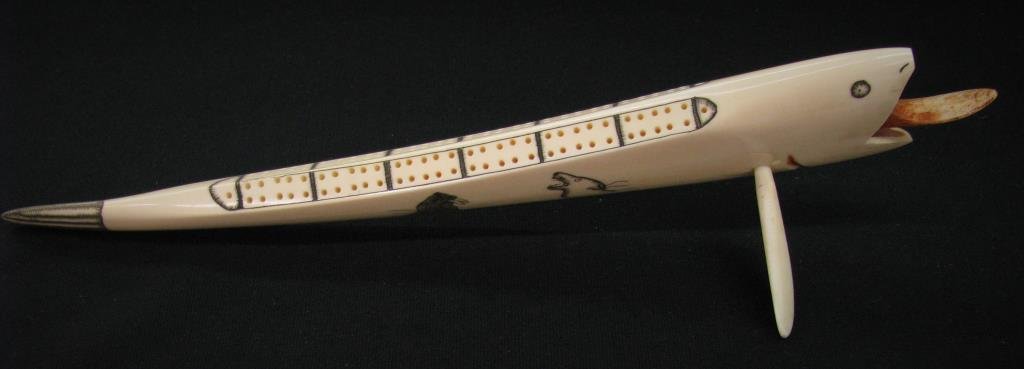 Inuit Tusk Carved Cribbage Game: Inuit style carved ivory tusk cribbage board, whale motif, 13" long, with fin-style foot, signed by "Charles Penatac, King Island"