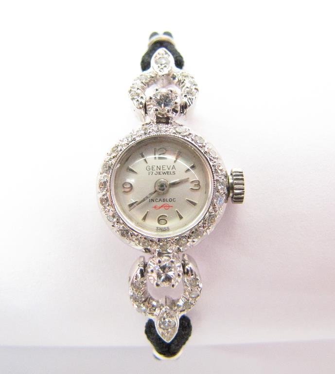 14K White Gold Geneva Watch, Diamond Band: Lady's 14K white gold Geneva watch with diamond bezel and side accents with black cord band, also includes second diamond band featuring round brilliant diamonds