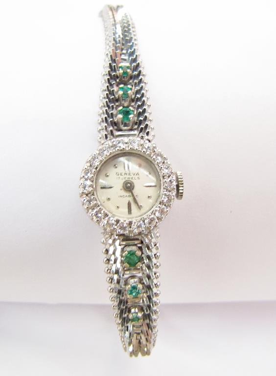 14K White Gold Geneva Watch, Emerald and Diamond: Lady's 14K white gold Geneva watch, with diamond bezel and emerald side stones (six) on band