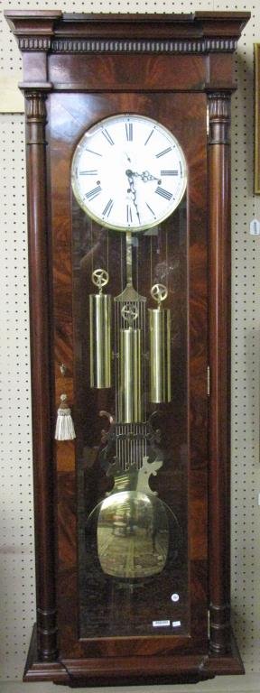 Sligh Longcase Wall Clock, Mahogany: A Sligh (Holland, MI) longcase wall-mount clock, mahogany case with burl veneer, dentil carved trim, tin porcelain face, key wind movement, brass weights and pendulum, beveled glass in door and on sid