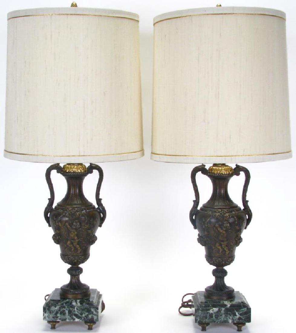 Pair of Frederick Cooper Bronze Urn Lamps: Pair of Frederick Cooper Bronze Urn Lamps, two handled urn form lamps with raised cherub and floral decoration, on square black and green marble bases, cream shades with acorn finials, 28" high