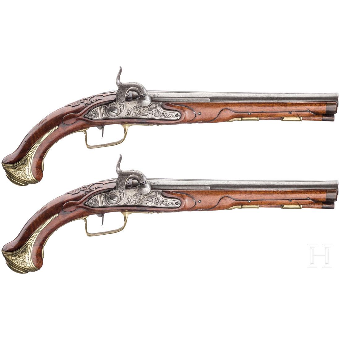 A pair of percussion pistols, German, ca. 1740/50: Runde LÃ¤ufe mit abgesetzter Mittelschiene, glatte Seelen im Kaliber 12 mm. Aptierte SchlÃ¶sser mit Rankengravur. Leicht verschnittene VollschÃ¤fte aus Nussbaumholz mit Nasen aus Horn. Fein grav
