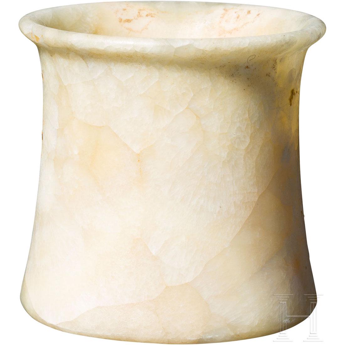 A Bactrian alabaster vessel, 2nd millenium B.C.: Slightly conical alabaster vessel with a deep interior cavity and a plateaued rim. Minimal traces of sinter on the creamy yellow alabaster. Slightly bumped at the rim. Wonderful patina. Intact. Height