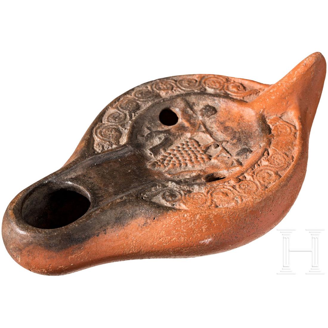 A Late Roman oil lamp with Caleb and Joshua carrying: Oil lamp with depiction of Caleb and Jushua carrying a huge wine grape. Intact. L. 14.1 cm. Cf. H. Dejean, Lampes Antiques Ã travers les Ages: Le Corpus (2012) pl. 133 L 844. Provenance: From a col