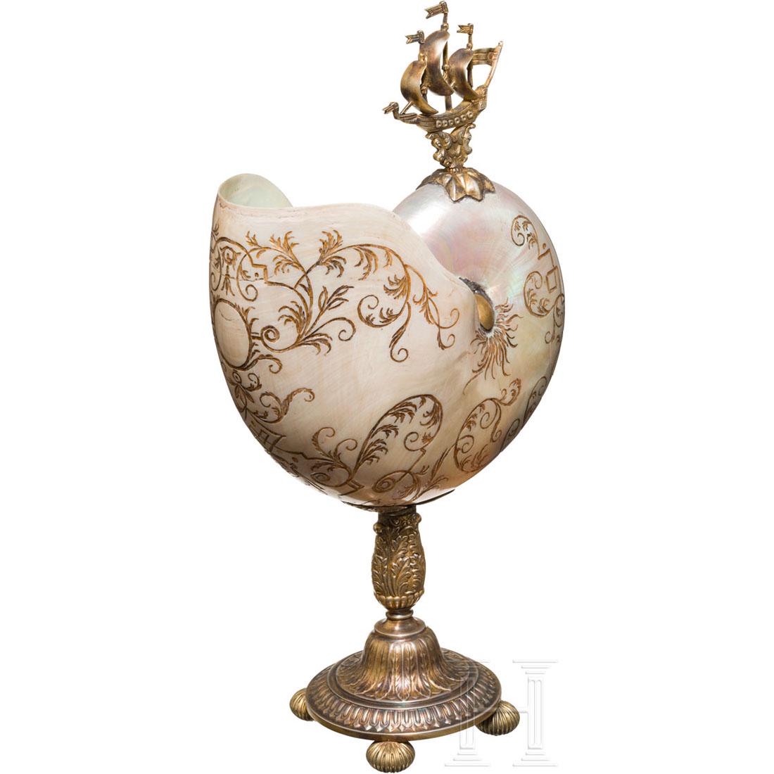 A large silver-mounted nautilus shell, 19th century: GroÃŸe Nautilus-Pompilius-Muschel mit perlmuttglÃ¤nzender OberflÃ¤che, diese reich graviert und vergoldet mit Neptun und floralen Ranken. Die Montierungen aus Silber mit Resten der Vergoldung, o
