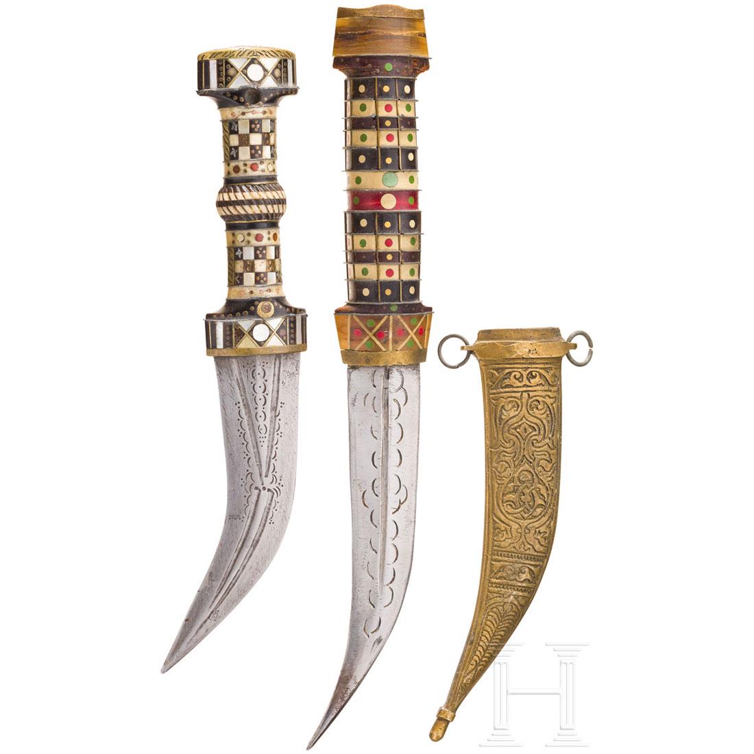 Two Syrian daggers, 19th/20th century: Jeweils zweischneidige, mehrfach gekehlte und leicht geschnittene Klinge. Griffe aus schwarzen Horn- und hellen Beinscheiben mit Einlagen aus Messing und Zinn. Ein Dolch mit floral geschnittener Messi