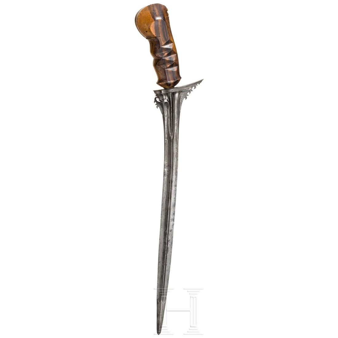 A Balinese chiselled kris, 19th century: Lange, leicht gekrÃ¼mmte und gegratete, zweischneidige Klinge mit schÃ¶nem, schwarz-weiÃŸem Pamor sowie beidseitig tief geschnittenem Ansatz. Der mÃ¤chtige Griff aus beschnitztem Timoho-Holz. 