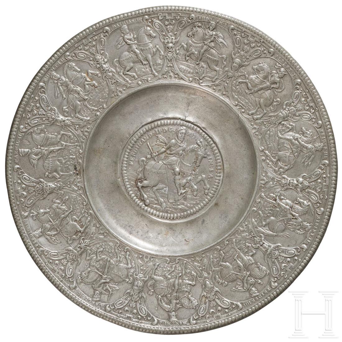 A tin plate with the motif of the coronation of: Reliefierter Zierteller aus Zinn. Im Spiegel Darstellung Kaiser Ferdinands II. zu Pferde, auf der Fahne umlaufend elf Reiterbildnisse seiner Vorfahren. In der Form geschnittene Marke des NÃ¼rnberger