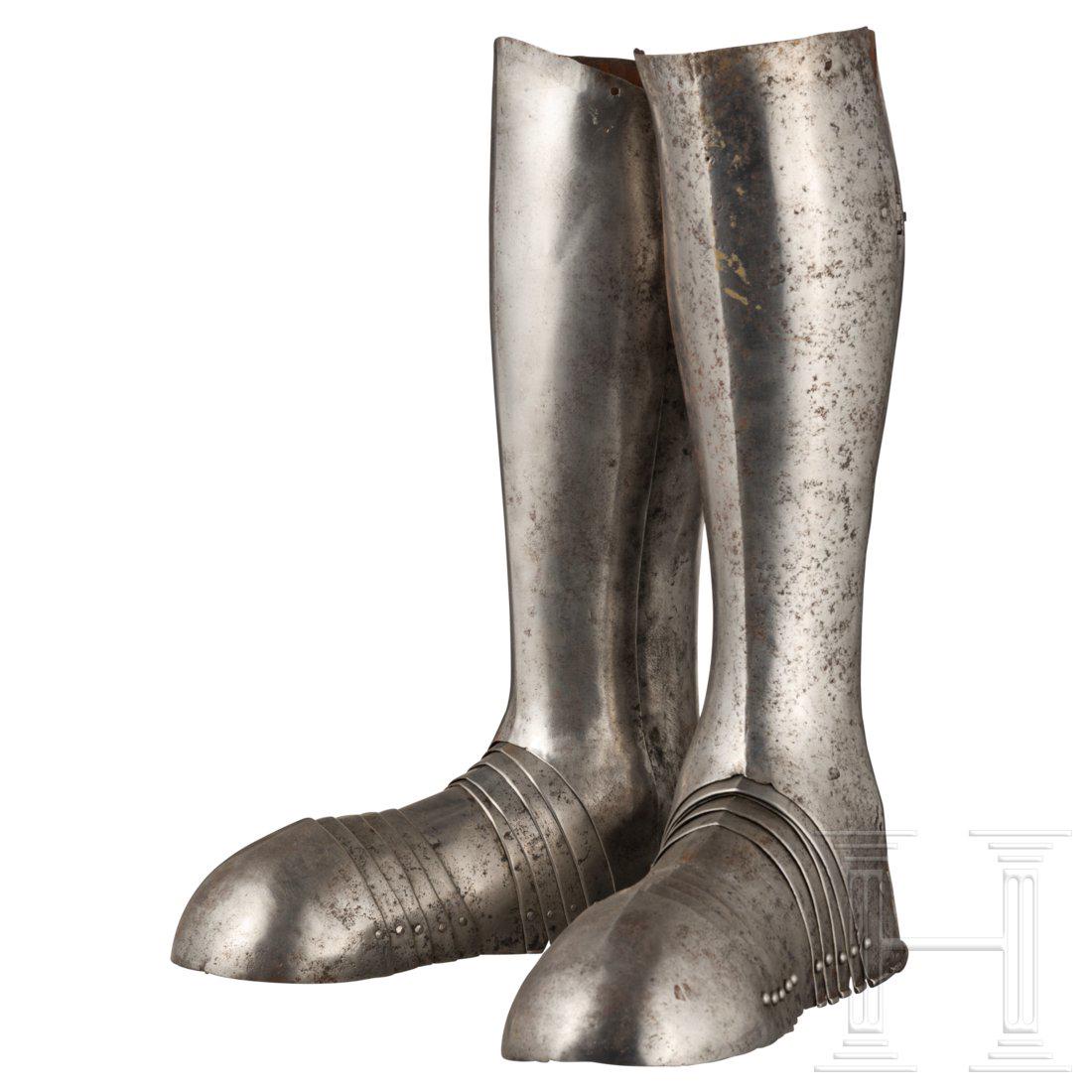 A pair of German leg armours with sabbatons, circa 1560: KrÃ¤ftig gegratete, im Scharnier zu Ã¶ffnende BeinrÃ¶hren mit herausgetriebenen KnÃ¶cheln. An der Ferse schlitzartige Aussparungen fÃ¼r die Sporen. Feine, nach auÃŸen gebÃ¶rdelte, teils 