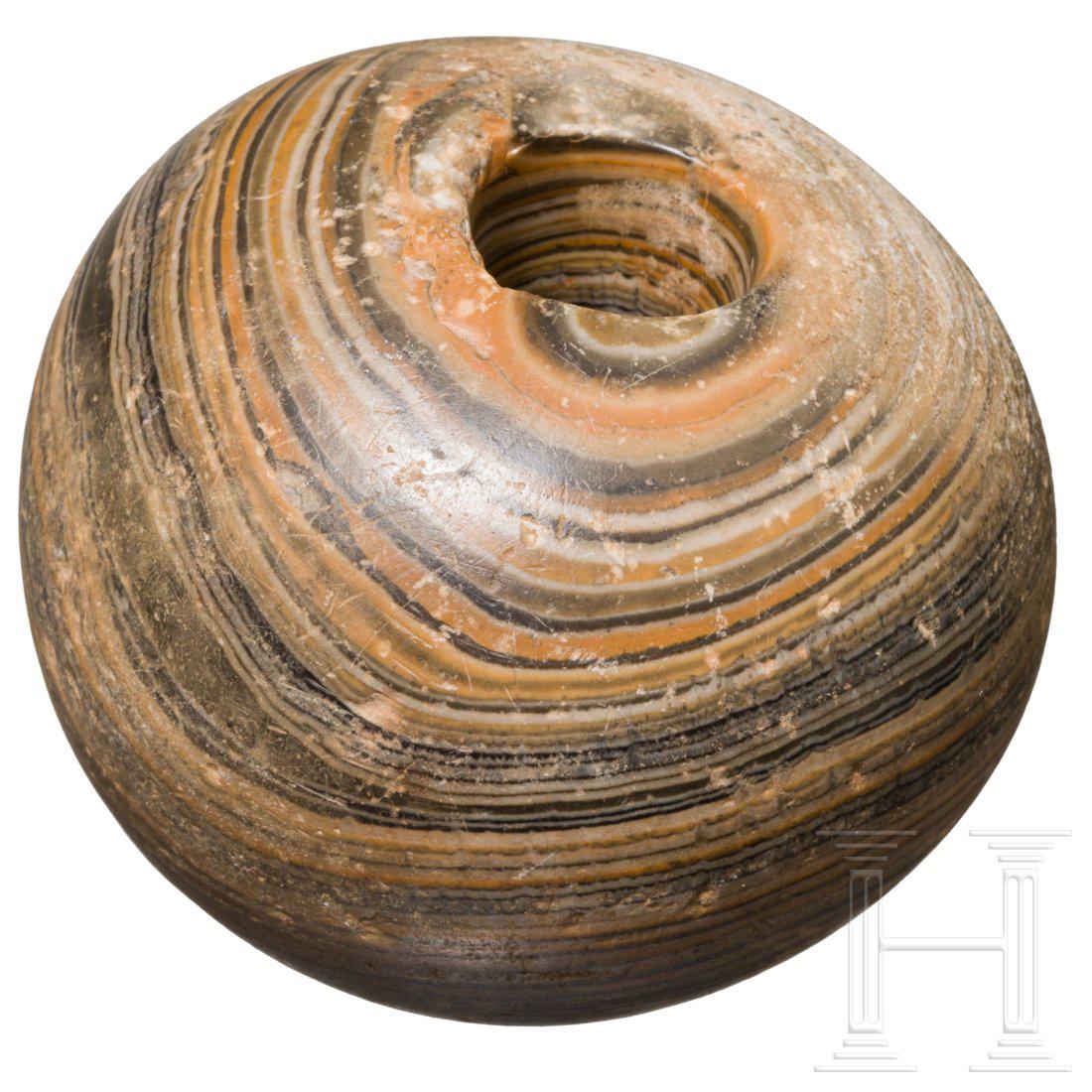 An Egyptian mace head, Old Kingdom, 2800 â€“ 2000 B.C.: Spherical mace head made of beautifully grained stone with a hole to receive a shaft. Diameter 9 cm. Provenance: Hermann Historica, Auktion 64, Los 3003. Condition: II
