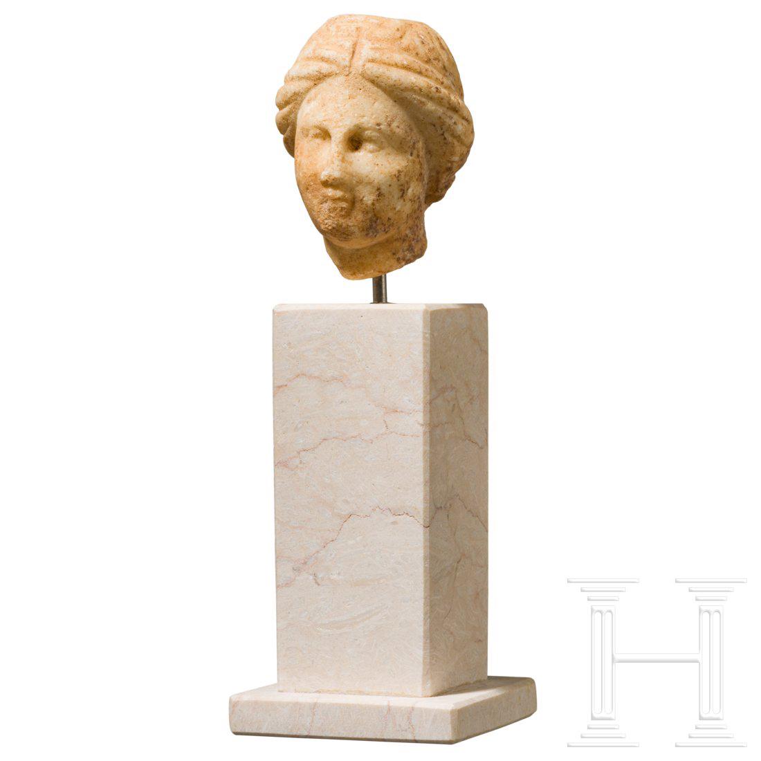 A small Hellenistic marble head, 3rd â€“ 2nd century: Small marble head of a woman with fine features. Broken at the neck. Tip of nose and chin slightly bumped. Height 5.5 cm, with base 15 cm. Provenance: Old private collection from Munich. Condition: II