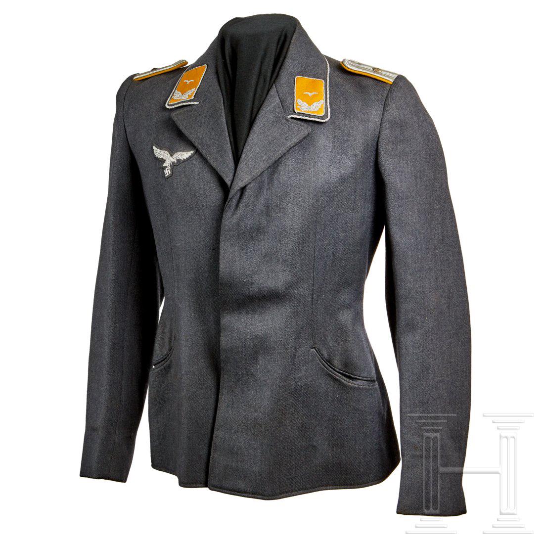 A Fliegerbluse for an officer: Luftwaffe blue-grey tricot wool, four hidden buttons (silver NSDAP), collar piped in aluminum twist cord, golden-yellow branch insignia and silver wire breast eagle hand-applied, shoulder boards are m