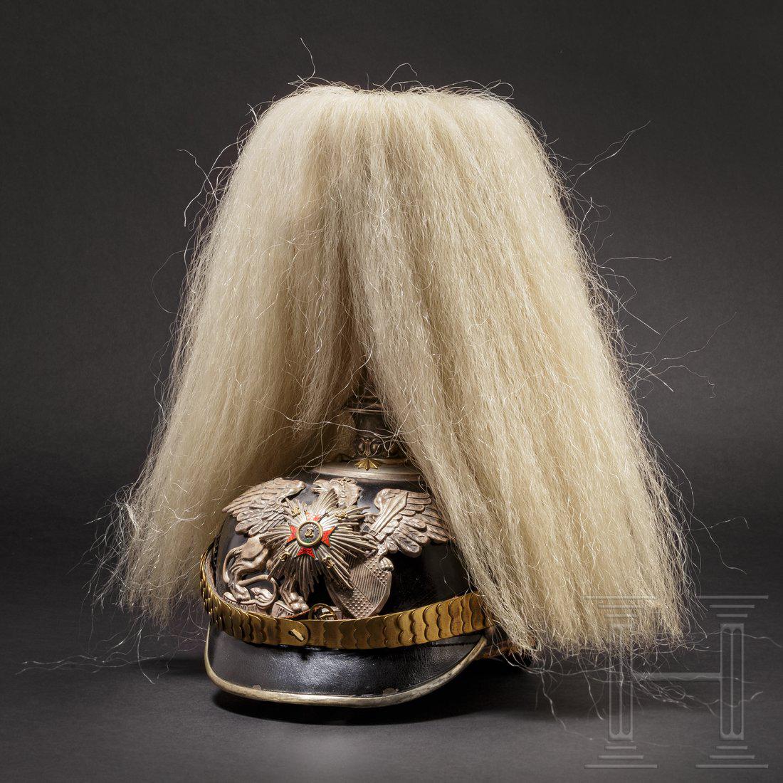 A helmet for officers of the 1st Baden Leib Grenadier: Schwarz lackierte Lederglocke (leicht krakeliert) mit runden Schirmen und versilberten NeusilberbeschlÃ¤gen. Verschraubtes Emblem (DoppellÃ¶cher) in Form des badischen Greifs mit aufgelegtem, emai