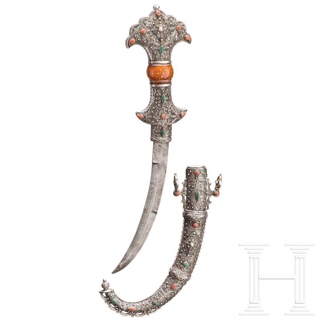Silbermontierte Koummya, Marokko, 19./20. Jhdt.: Typisch geformte, an der Spitze zweischneidige, gekrÃ¼mmte RÃ¼ckenklinge. Griff und Scheide aus Silber mit aufwÃ¤ndigem Silberfiligran-Dekor, schauseitig mit farbigen Schmucksteinen besetzt, der