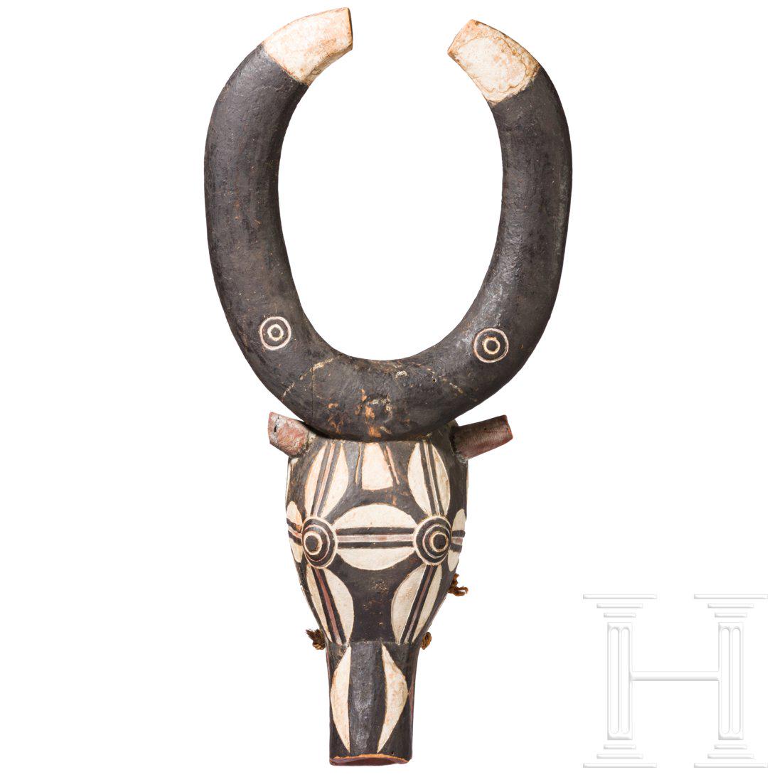 A buffalo mask of the Bwa people from Burkina Faso: Polychrom gefasste Kopfmaske in Form eines stilisierten BÃ¼ffelkopfes mit ausladenden, geschwungenen HÃ¶rnern (ein Horn mit repariertem Bruch). Der untere Teil der Maske zur Anbringung des Naturfa