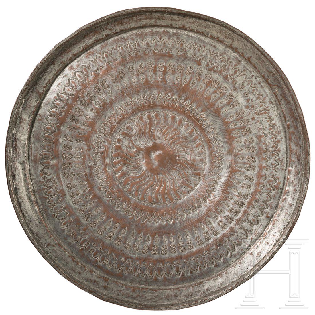 An Ottoman plate, 1st half of the 20th century: Mittig eingezogenes, rundes Tablett aus verzinntem Kupfer mit gebÃ¶rdeltem Rand. Die Schauseite reich punziert mit geometrisch umlaufendem Muster. Durchmesser 57,3 cm. Condition: II -
