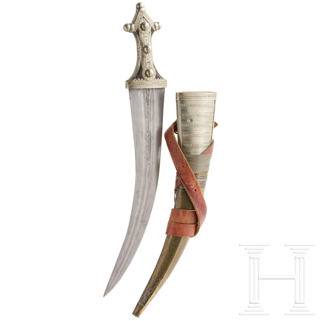 A Saudi Arabian Wahabite djambiya, first half of the: Zweischneidige, beidseitig doppelt gekehlte und am Ansatz geometrisch gravierte Klinge. Neusilbermontierter Horngriff mit schauseitig halbrunden Ziernieten. Messing- und neusilberÃ¼berzogene Holzsch