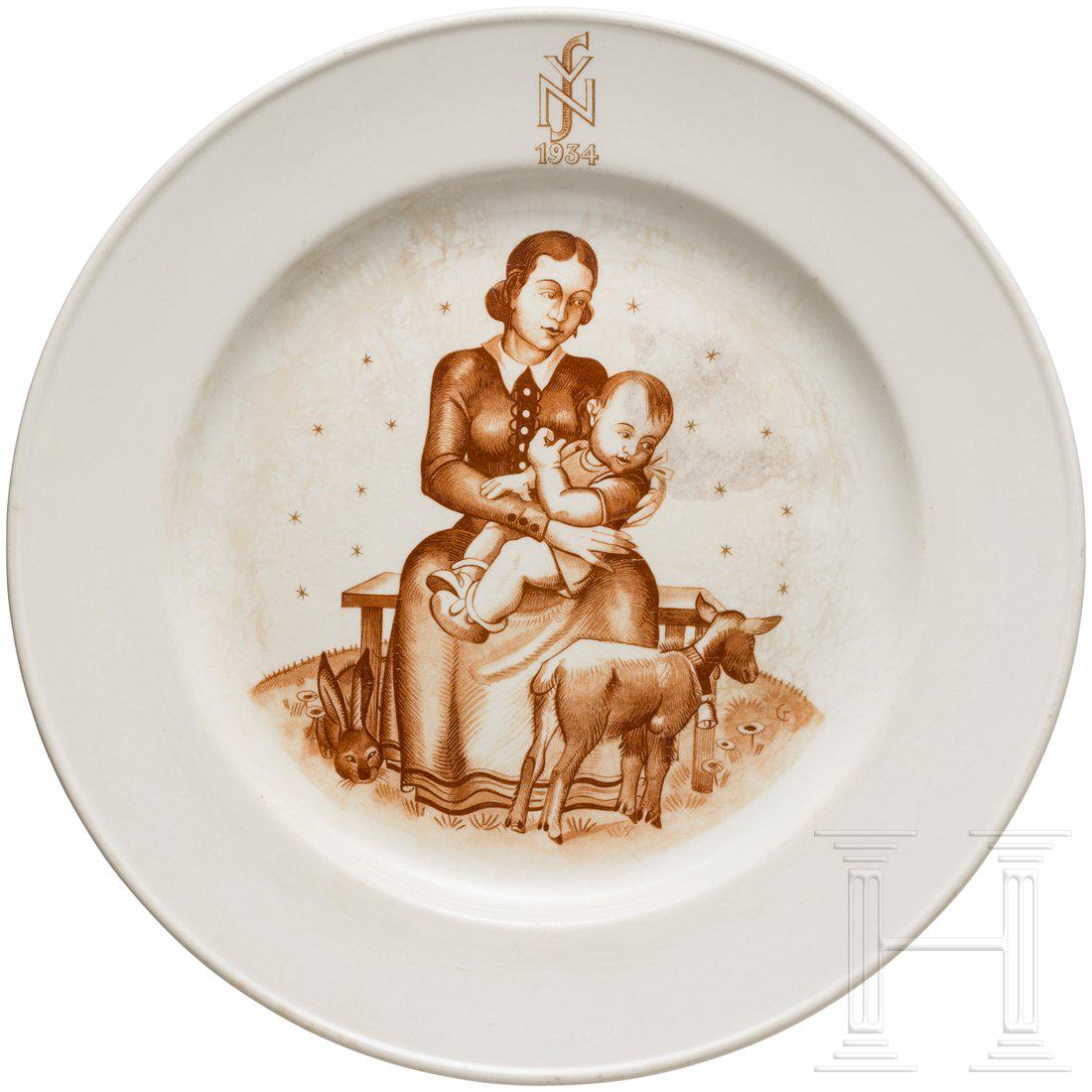 NSV-Wandteller, Gau 10 Hessen-Nassau: Glasierter, weiÃŸer Steingutteller. Motiv und Schrift in Sepiabraun. Motiv: Mutter mit einem auf dem SchoÃŸ sitzenden Kind. Daneben Ziege mit GlÃ¶ckchen und Hase. Im Hintergrund Sterne. Am Telle