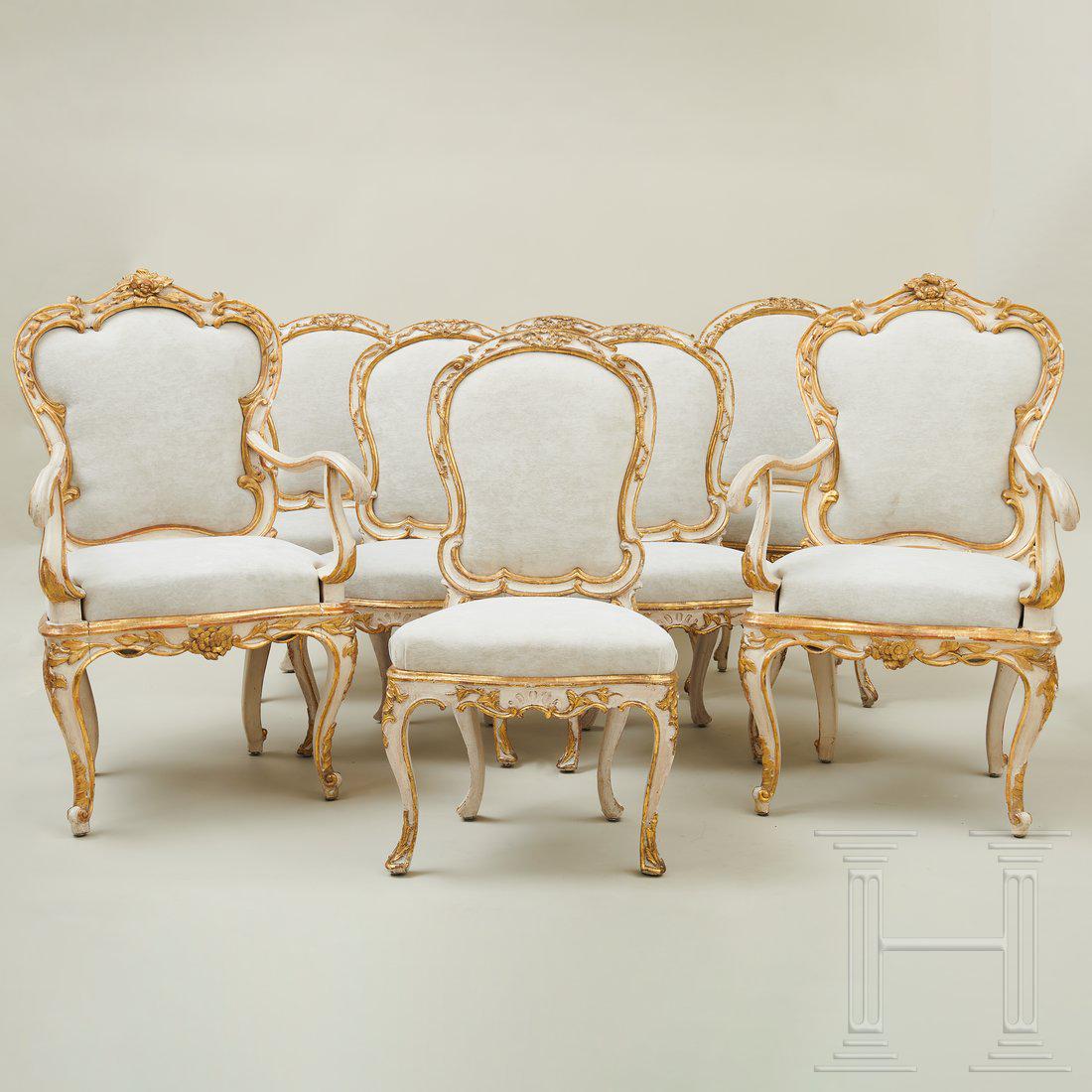A set of Venetian dining room chairs, 2nd half of the: Eight chairs, two with armrests, on capriole legs with trapezoidal seats and rounded backrests. The chairs are painted a creamy white and embellished with gold patinated C-shaped buckles, bows and ban