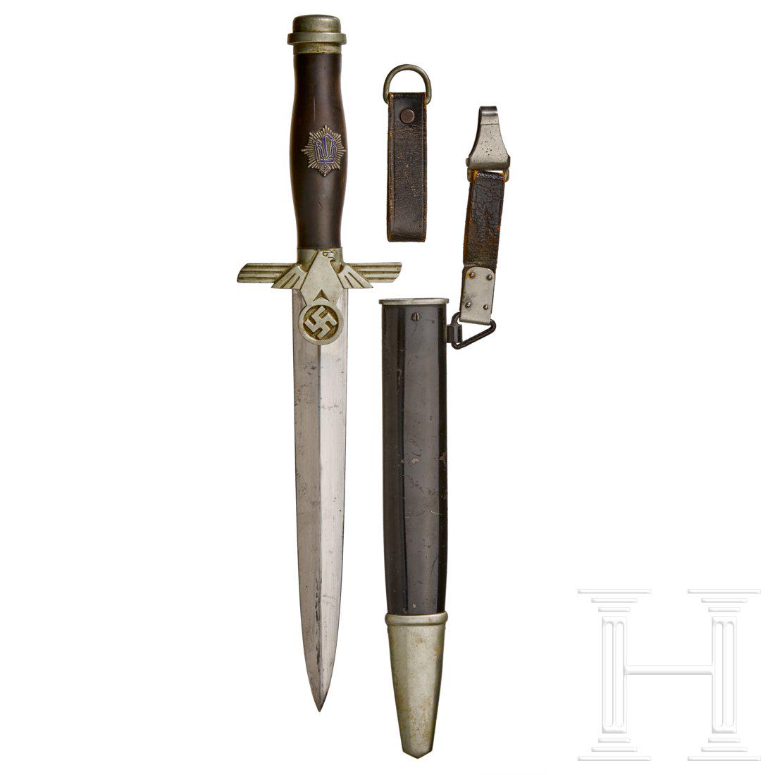 A Model 1936 Dagger for Subordinate Leaders of the RLB: Maker Gustav Spritzer, Solingen, polished steel blade with etched manufacturerâ€™s logo. Nickel-silver cross-guard and pommel. Black wooden grip with enamelled RLB emblem. Black-lacquered steel s